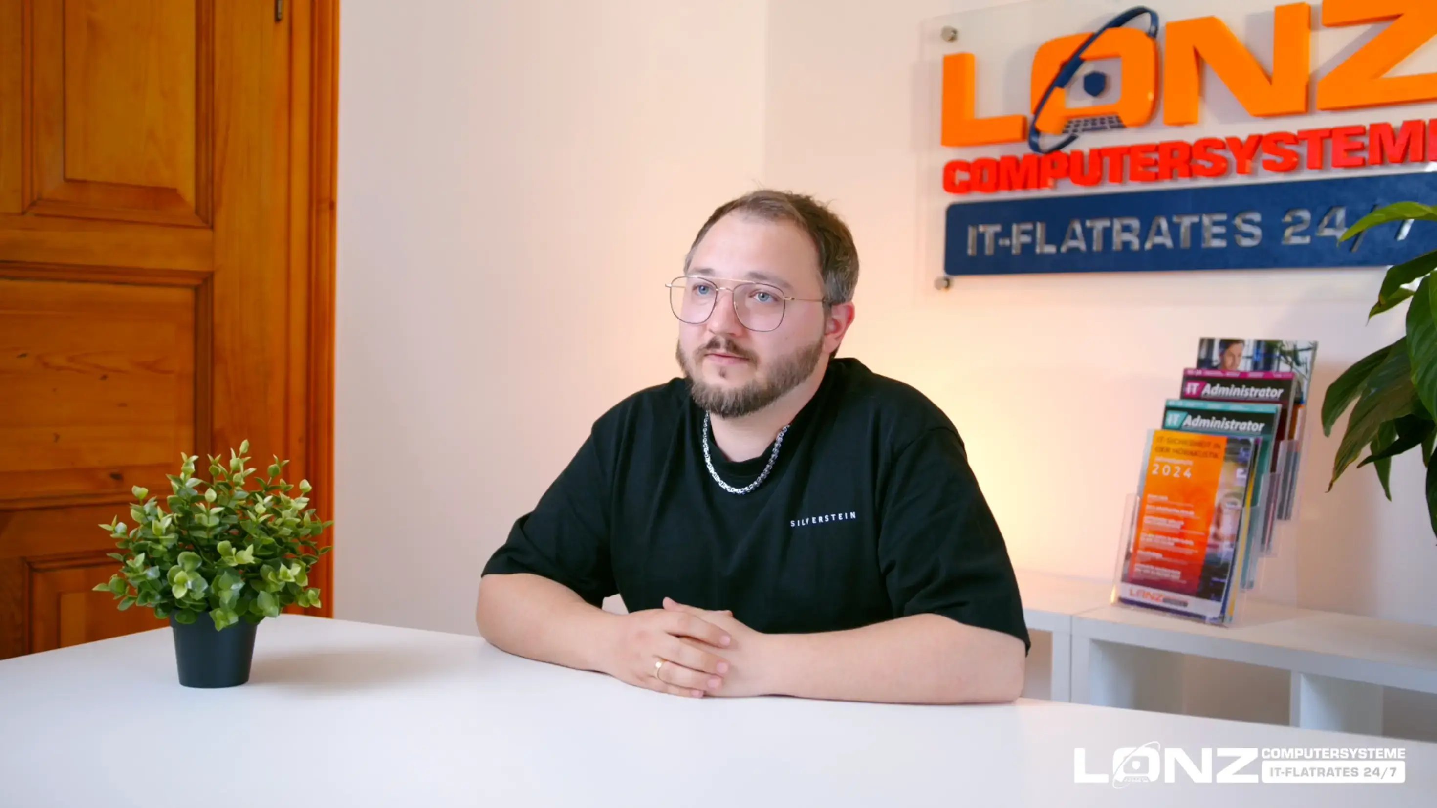 Video-Vorschaubild von Dominik, Mitarbeiter bei ComputerSysteme Lonz. Er sitzt an einem weißen Schreibtisch, spricht und gestikuliert während eines Interviews. Im Hintergrund ist das Firmenlogo zu sehen.